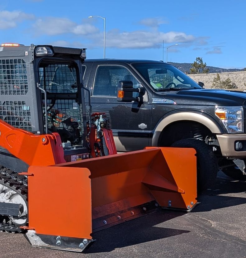 Kubota loader and BOSS plow truck in a cleared lot