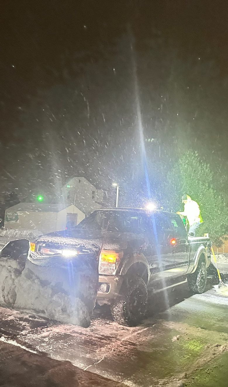 Red Beard's plow truck clearing a parking lot at night during a snowstorm