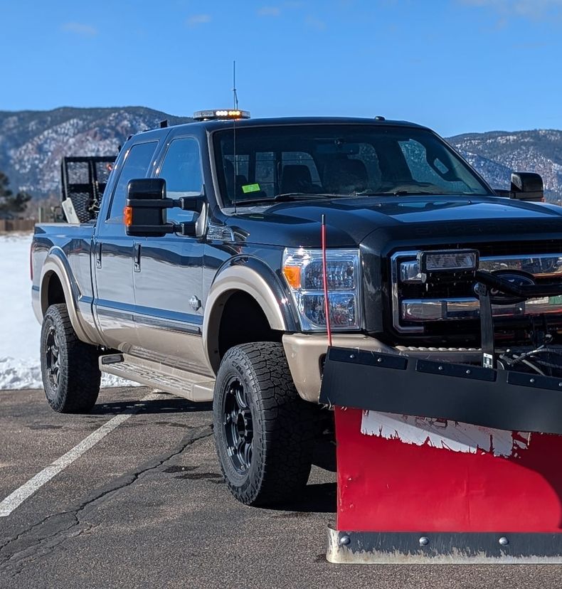 Plow truck in front of snowy foothills near Monument